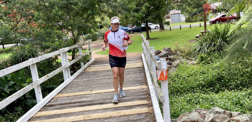 Lady running over a bridge towards an orange and white flag